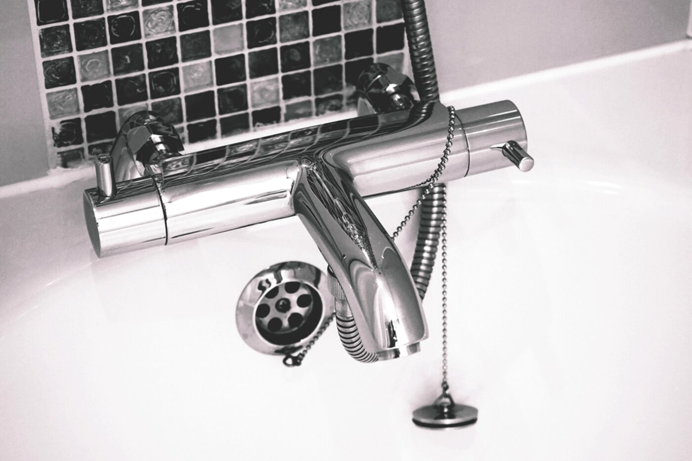 A chrome bath tap and mixer against white tiles