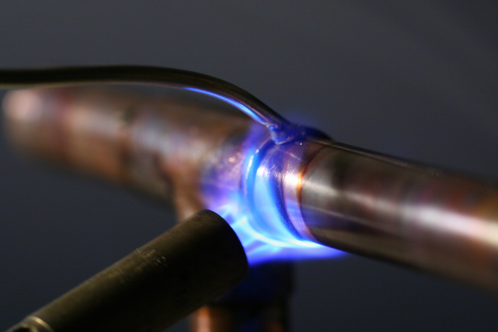 A blowtorch heating a copper pipe joint